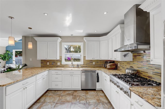 kitchen with wall chimney range hood, sink, kitchen peninsula, appliances with stainless steel finishes, and white cabinetry