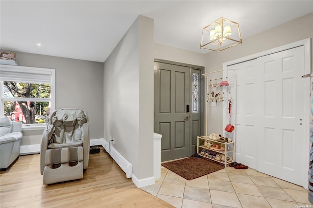 entrance foyer with light wood-type flooring, baseboard heating, and a notable chandelier