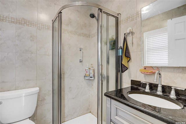 bathroom with tile walls, vanity, an enclosed shower, and toilet