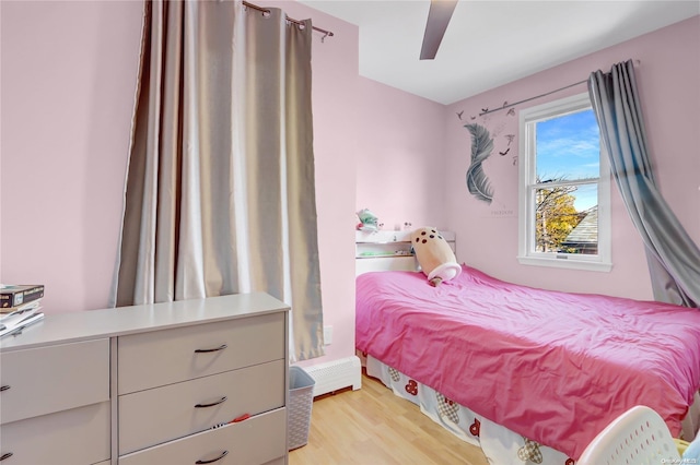 bedroom with ceiling fan, light hardwood / wood-style flooring, and a baseboard radiator