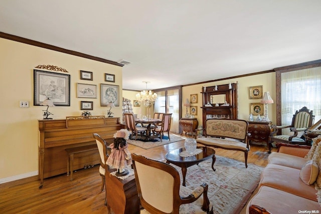 living room featuring plenty of natural light, light wood-type flooring, ornamental molding, and an inviting chandelier