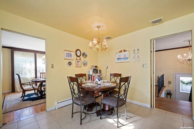 dining space with light hardwood / wood-style floors, a baseboard radiator, and an inviting chandelier