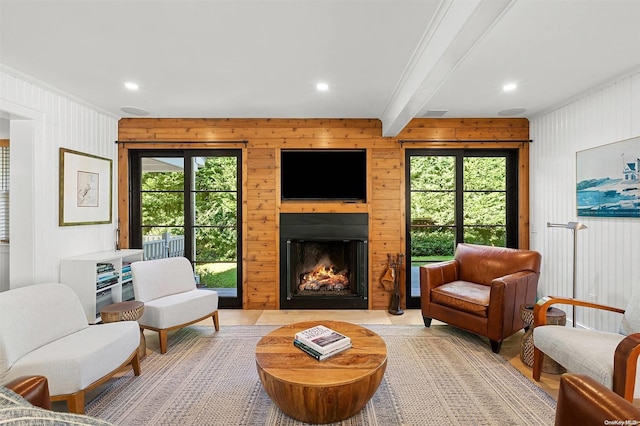 living area featuring beamed ceiling, a wealth of natural light, and ornamental molding