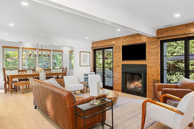 living room featuring wood walls, beam ceiling, light wood-type flooring, and a wealth of natural light