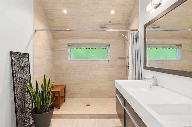 bathroom with a wealth of natural light, curtained shower, tile patterned floors, vanity, and tile walls