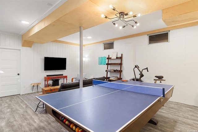 playroom with hardwood / wood-style flooring, wood walls, and an inviting chandelier