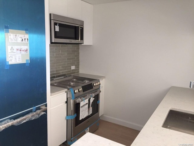 kitchen featuring white cabinetry, sink, dark hardwood / wood-style flooring, decorative backsplash, and appliances with stainless steel finishes