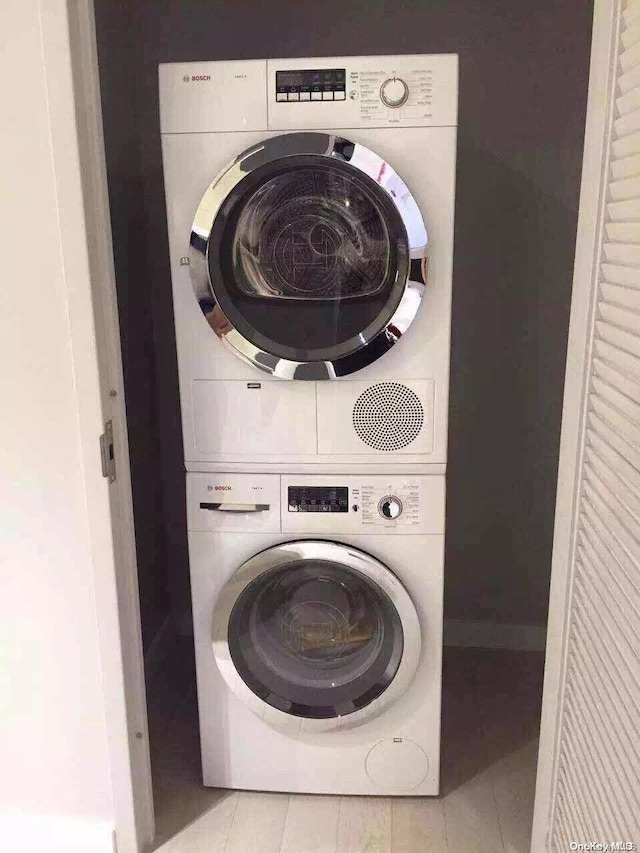 clothes washing area with light tile patterned floors and stacked washer / dryer