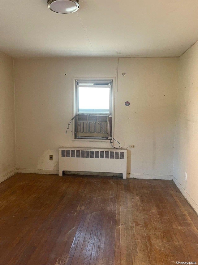 unfurnished room featuring radiator heating unit and dark hardwood / wood-style floors