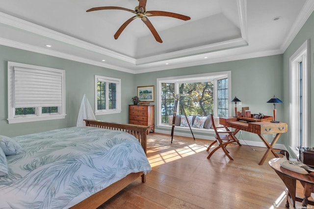 bedroom featuring ceiling fan, light hardwood / wood-style floors, a raised ceiling, and crown molding