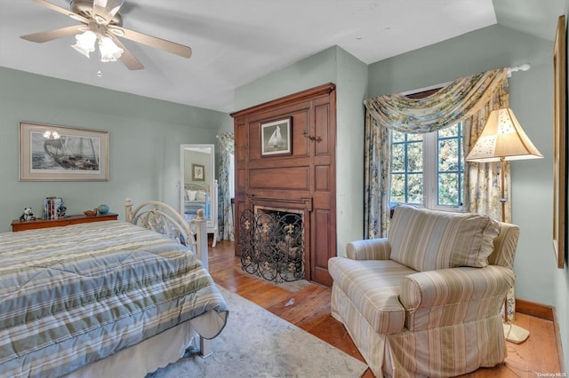 bedroom with ceiling fan, vaulted ceiling, and light wood-type flooring