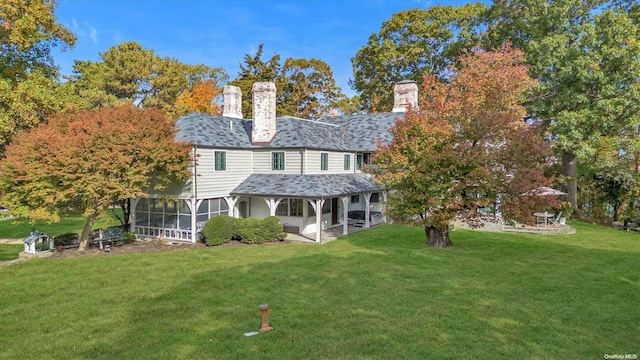 rear view of house featuring a lawn, a sunroom, and a patio