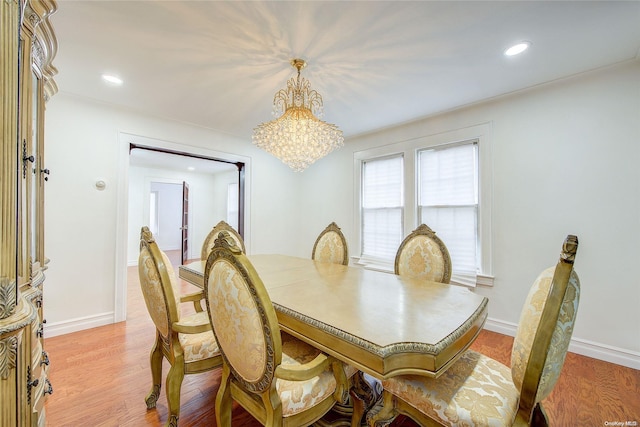 dining area with light hardwood / wood-style floors and a notable chandelier