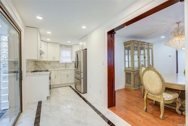 kitchen with decorative backsplash, light hardwood / wood-style floors, white range oven, white cabinetry, and stainless steel refrigerator