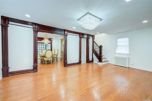 interior space featuring decorative columns, light hardwood / wood-style flooring, radiator, and a notable chandelier