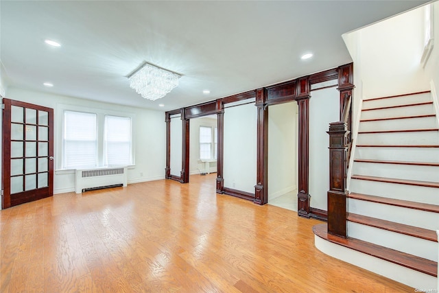 unfurnished room with light hardwood / wood-style floors, radiator, and an inviting chandelier