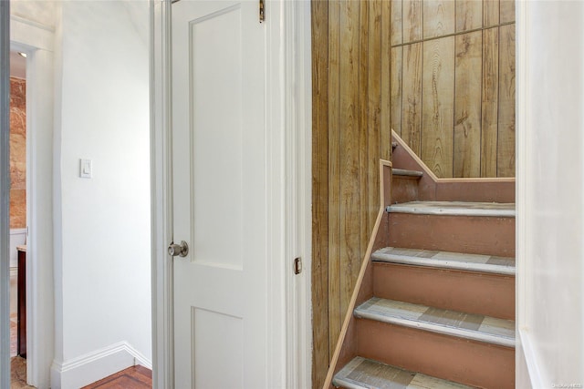 stairway featuring wooden walls