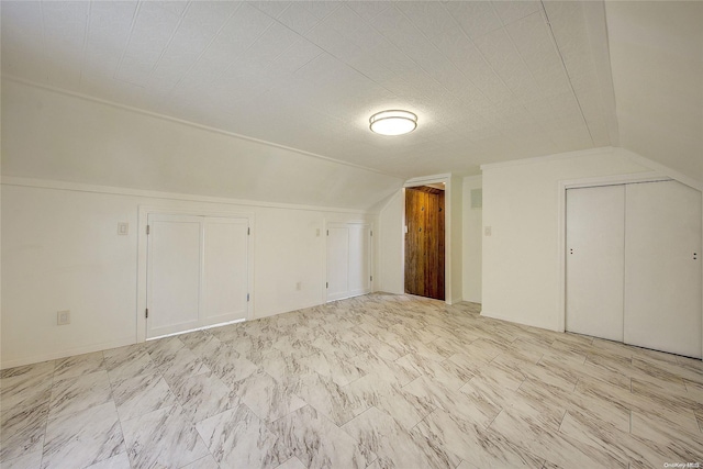 additional living space featuring a textured ceiling and vaulted ceiling