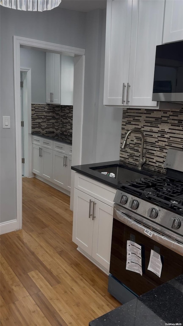 kitchen featuring tasteful backsplash, range with gas cooktop, sink, white cabinets, and light hardwood / wood-style floors