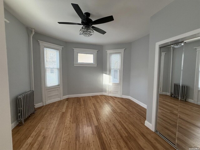 spare room featuring ceiling fan, light wood-type flooring, and radiator heating unit