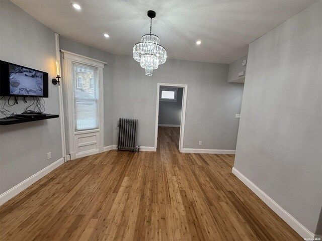 unfurnished dining area with radiator heating unit, a chandelier, and light hardwood / wood-style flooring