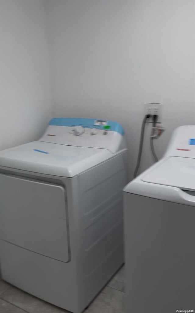 laundry area with light tile patterned flooring and washer and dryer