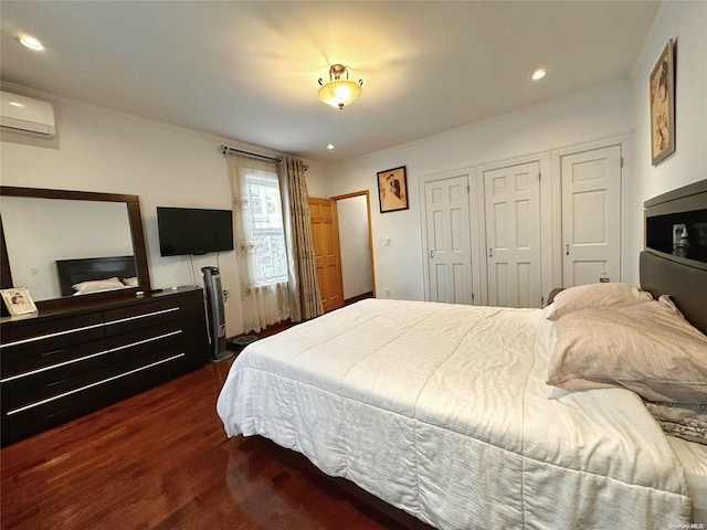 bedroom featuring dark hardwood / wood-style flooring, a wall mounted AC, and multiple closets