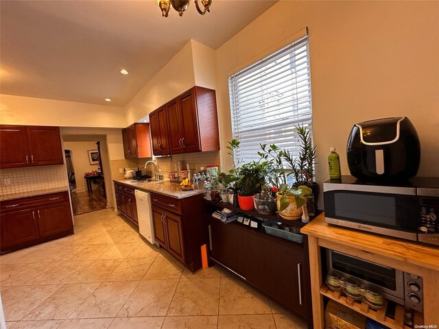 kitchen with white dishwasher, decorative backsplash, light tile patterned floors, and sink