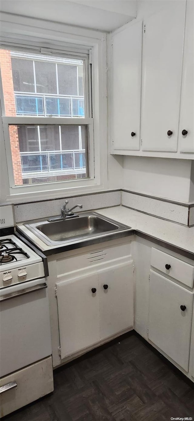 kitchen featuring sink, white cabinets, dark parquet floors, and white range