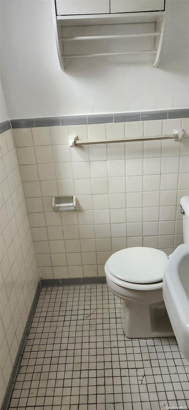 bathroom featuring tile patterned flooring, toilet, and tile walls