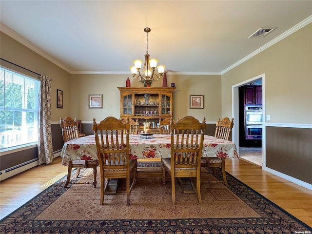 dining space featuring light wood-type flooring, crown molding, and an inviting chandelier