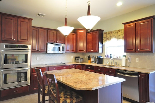 kitchen with a center island, backsplash, sink, appliances with stainless steel finishes, and decorative light fixtures