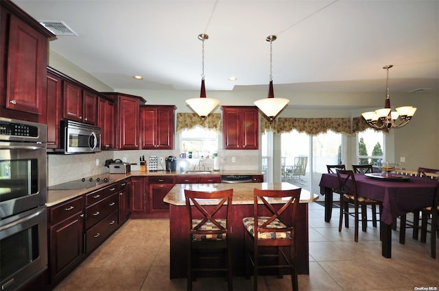 kitchen featuring a breakfast bar, stainless steel appliances, decorative light fixtures, a chandelier, and a center island