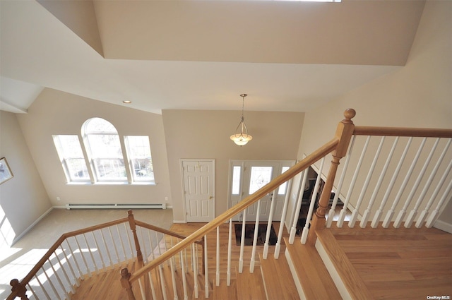 staircase with a baseboard radiator, a healthy amount of sunlight, lofted ceiling, and hardwood / wood-style flooring