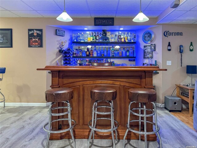 bar with pendant lighting, a paneled ceiling, and hardwood / wood-style flooring