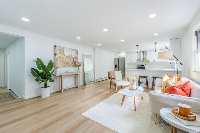 living room featuring sink, light hardwood / wood-style flooring, and a baseboard heating unit