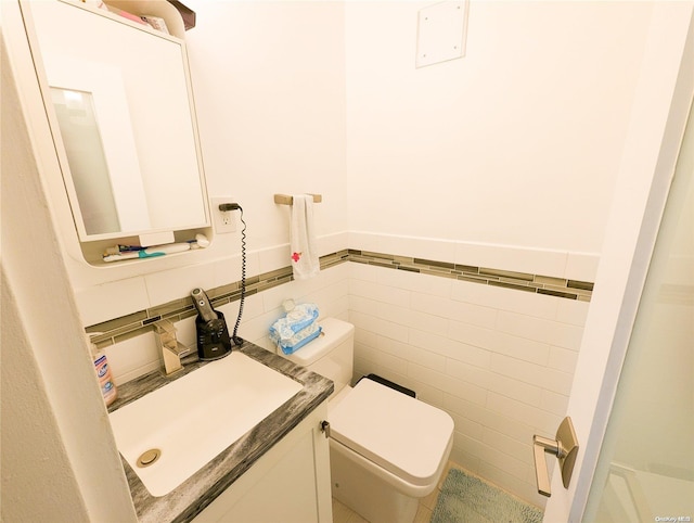 bathroom with vanity, toilet, and tile walls