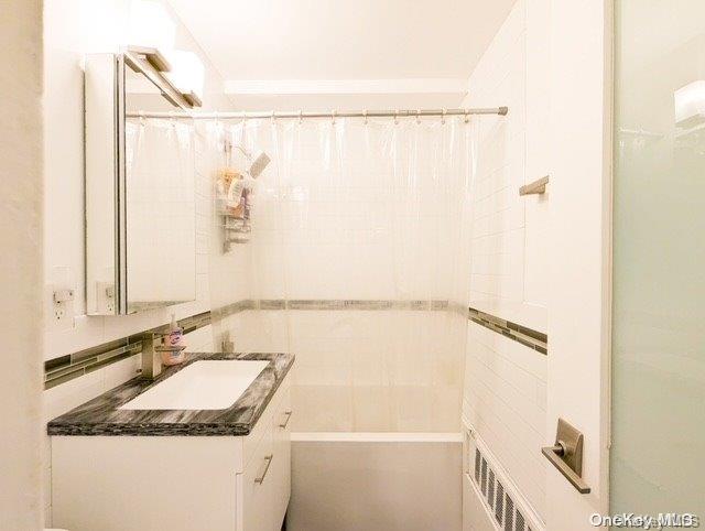 bathroom featuring vanity, shower / bath combo with shower curtain, and backsplash