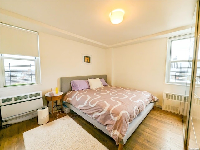 bedroom with radiator, heating unit, a wall mounted AC, and dark hardwood / wood-style floors