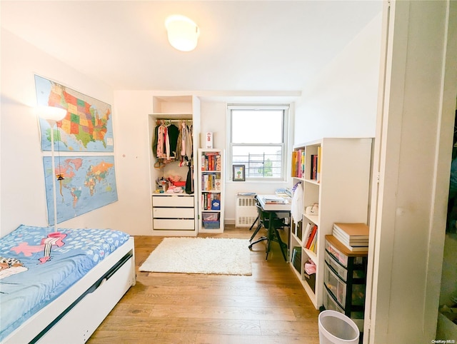 bedroom with radiator, a closet, and light hardwood / wood-style floors