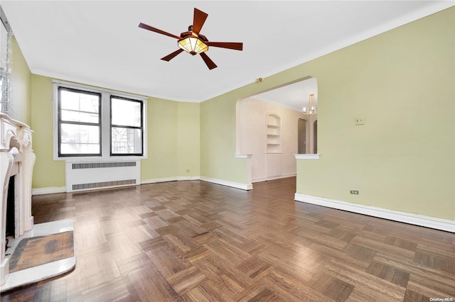 unfurnished living room featuring radiator heating unit, dark parquet floors, and ceiling fan with notable chandelier