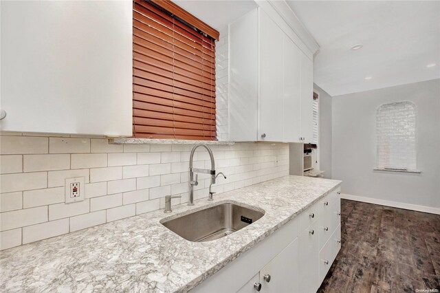 kitchen featuring white cabinets, light stone counters, sink, and dark wood-type flooring