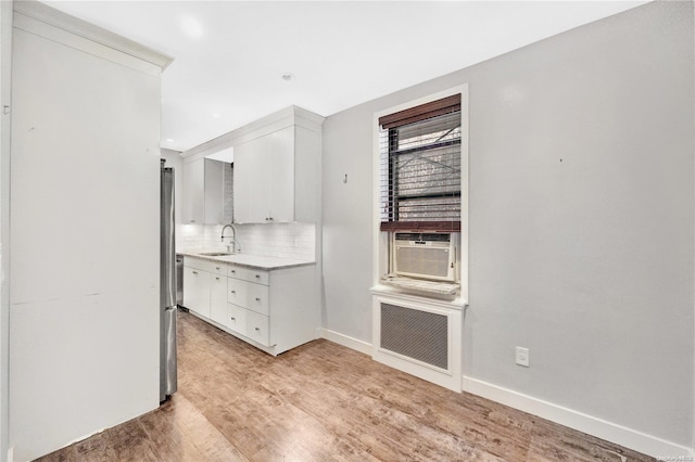 kitchen featuring cooling unit, sink, decorative backsplash, light hardwood / wood-style floors, and white cabinetry