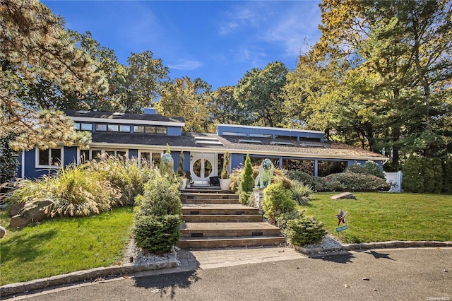 view of front of property featuring a front lawn and solar panels