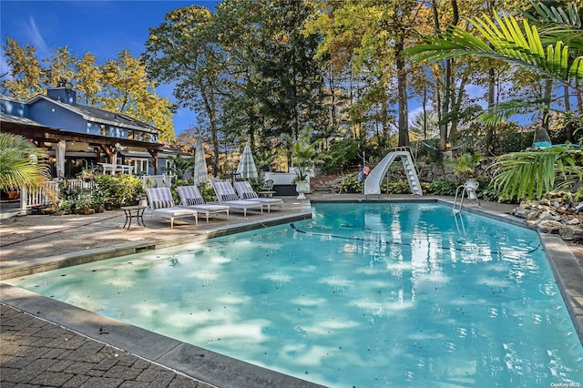 view of swimming pool with a patio and a water slide