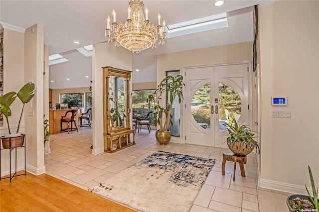 entrance foyer featuring french doors, light hardwood / wood-style floors, and an inviting chandelier