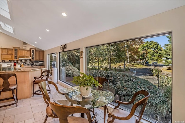 dining room featuring a wealth of natural light, light tile patterned floors, and vaulted ceiling