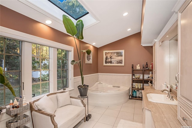 bathroom with tile patterned flooring, vanity, a relaxing tiled tub, and vaulted ceiling with skylight