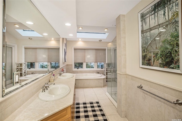 bathroom featuring separate shower and tub, lofted ceiling with skylight, tile patterned flooring, and vanity