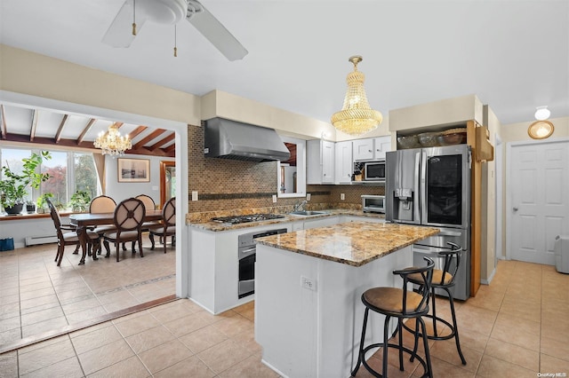 kitchen featuring wall chimney range hood, decorative backsplash, decorative light fixtures, white cabinetry, and stainless steel appliances